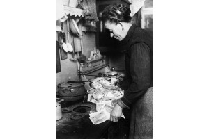 O femeie foloseste bancnote pentru a aprinde focul din soba